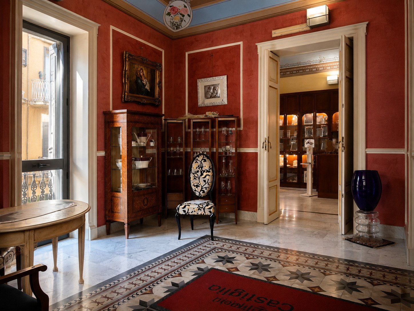 La sala principale del piano superiore, con la vetrina intarsiata, porcellane e cristalleria